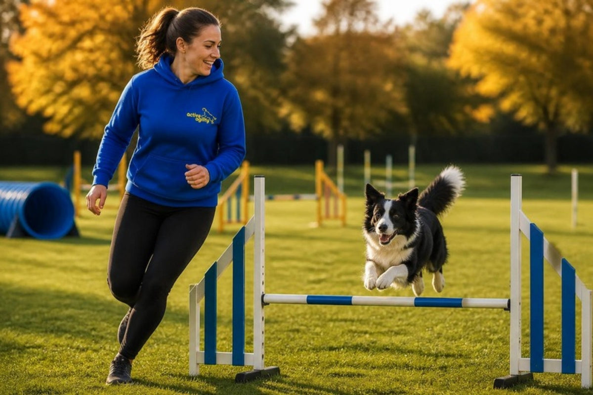 Handler in an Active Agility hoodie running beside her dog over an agility jump
